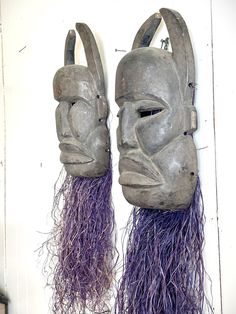 two masks with purple hair hanging on a wall