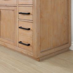 a wooden cabinet with black handles and drawers