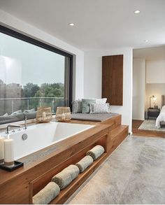 a bathroom with a large bathtub sitting next to a window and a bed in front of it