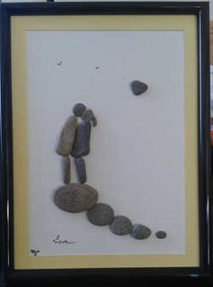 there is a framed picture with rocks in the shape of a man and woman holding hands