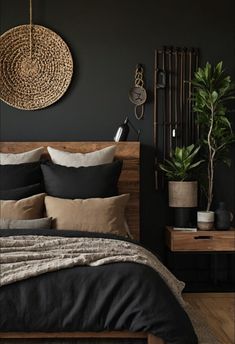 a bed with black sheets and pillows in a dark room next to a potted plant