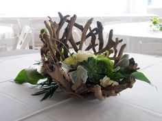 an arrangement of flowers and greenery on a table at a wedding or reception venue