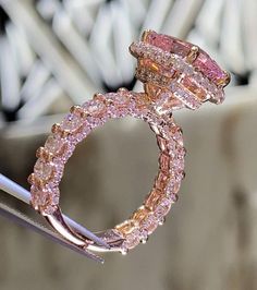 a pink diamond ring sitting on top of a piece of metal