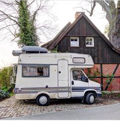 an rv is parked in front of a house with a tree on the side of it