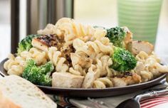 pasta with chicken and broccoli on a black plate next to some slices of bread