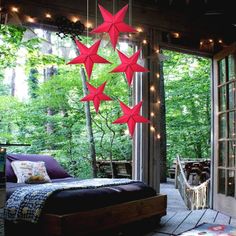 an outdoor bedroom with red stars hanging from the ceiling and lights on the outside wall