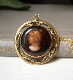 Vintage brown glass lady cameo pendant necklace. This unsigned necklace is circa-1960's.  Goldtone metal with brown glass background.  Cameo is glass, I think. Chain measures 16" and closes with a spring-lock clasp. Wonderful Victorian look to this.  In great shape! Sorry, but no international shipping at this time. Please see my shop for more vintage, estate jewelry: nightowlmemories.etsy.com Victorian Brown Collectible Jewelry, Vintage Brown Jewelry Gift, Victorian Style Brown Collectible Jewelry, Vintage Oval Cameo Necklace, Vintage Intaglio Pendant Jewelry, Formal Cameo Brass Necklace, Formal Brass Cameo Necklace, Formal Bronze Cameo Jewelry, Vintage Brown Necklace For Gifts