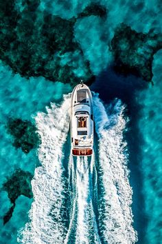 an aerial view of a boat traveling through the blue water with corals in the background