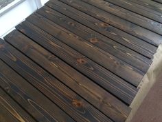 a close up of a wooden floor next to a white door and window with wood slats on it