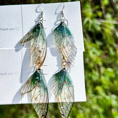 the earrings are made out of glass and have green leaves hanging from it's sides