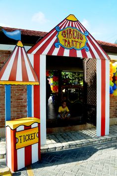 a carnival booth with clowns and balloons on the side walk in front of it