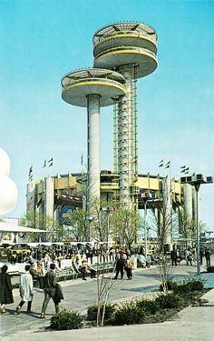 an old photo of people walking around in front of a large building with tall towers