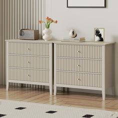 a white dresser with two vases on top of it next to a mirror and pictures