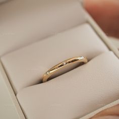 a gold ring with three diamonds in it sitting inside a white box on top of a table