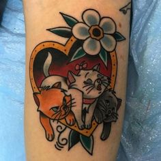 a couple of cats sitting on top of a heart shaped tattoo