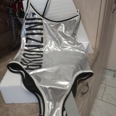 Brand New/Never Worn 1pc 'Revamped By Sirens' 1pc Silver Metallic Bathing Suit That's Embellished With The Word 'Bronzing' Down The Right Side In Black Bold Lettering. Size (M). Shiny Summer Bodysuit For Club, Silver Shiny Stretch Bodysuit, Metallic Sleeveless Bodysuit For Summer, Summer Metallic Sleeveless Bodysuit, Silver Fitted Bodysuit For Summer, Fitted Silver Bodysuit For Summer, Shiny Swimwear For Club In Summer, Metallic Swimsuit For Beach In Summer, Fitted Silver Swimwear For Summer