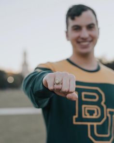 a young man in a green and gold shirt pointing at the camera with his finger