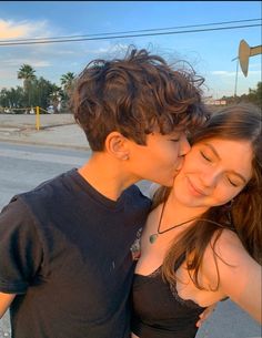 a young man and woman kissing on the street