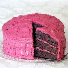 a chocolate cake with pink frosting is cut in half on a white tablecloth