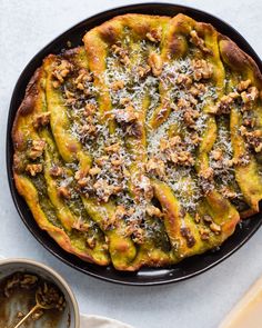 a pizza sitting on top of a pan covered in cheese and toppings next to a bowl