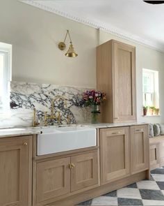 a kitchen with marble counter tops and wooden cabinets, gold faucets and brass fixtures