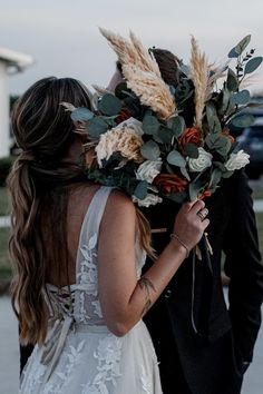 a bride and groom are walking together with flowers in their hair at the same time