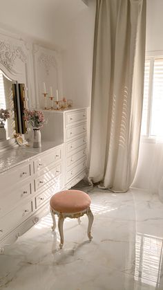 a large white bathroom with marble floors and walls, along with an ottoman in the middle