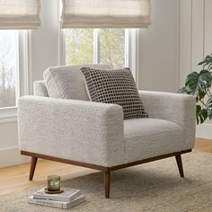 a living room scene with focus on the arm chair and coffee table in front of the window