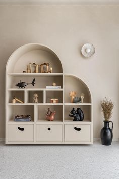 a white bookcase with many shelves and vases