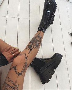 a woman sitting on the floor with her legs crossed and tattoos all over her body