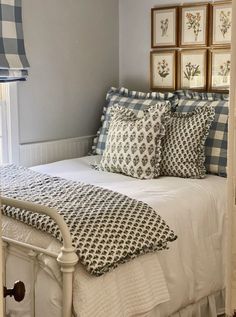 a white bed topped with lots of pillows next to framed pictures on the wall above it