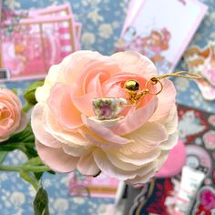 a pink flower sitting on top of a table next to some cards and flowers in a vase