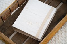 an open book sitting in a wooden box on top of a white carpeted floor