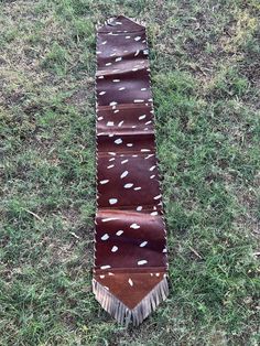 a brown and white tie laying on top of a grass covered field next to a patch of dirt