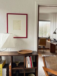 a living room with a book shelf, lamp and pictures on the wall above it