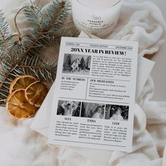 an open magazine sitting on top of a table next to a candle and some pine branches