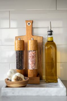 spices and oil are on the counter next to a cutting board with pepper grinds