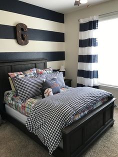 a black and white striped wall in a bedroom with a bed, window, and nightstand