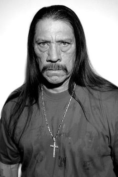 a black and white photo of a man with long hair, wearing a cross necklace