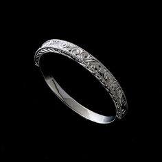 a wedding band with intricate designs on it's sides, against a black background