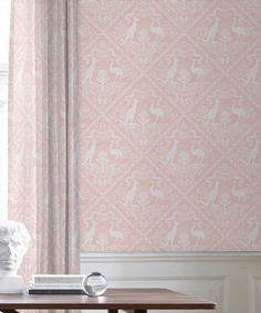 a table with a vase and some books on it next to a window covered in curtains