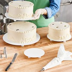 a woman in an apron is decorating three cakes