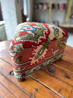 a colorfully decorated ottoman sitting on top of a wooden table