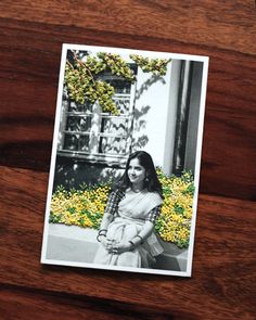 a black and white photo of a woman holding a baby in her arms on top of a wooden table