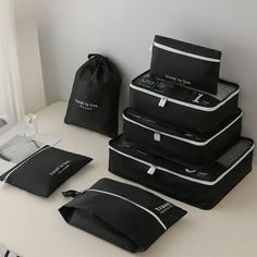 five pieces of black luggage sitting on top of a white table next to a bag