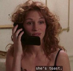 a woman talking on a cell phone while wearing a bra and black tank top with the words she's toast