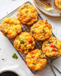 several small muffins on a cooling rack next to a fork and cup of coffee