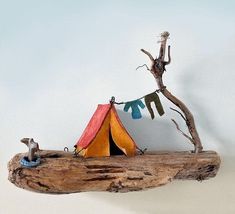 a wooden branch with a tent on it and a cat figurine next to it