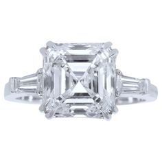 an emerald cut diamond ring with baguets on the shoulders and side stones in white gold