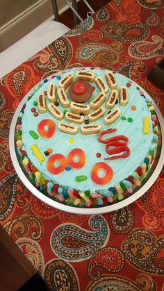 a birthday cake decorated with doughnuts and pretzels on a tablecloth